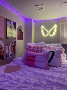 a bed with purple sheets, pillows and pictures on the wall above it in a bedroom