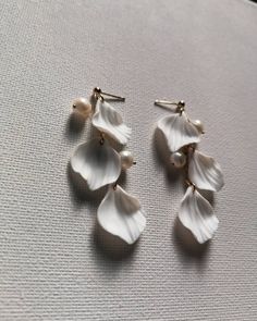 Indulge in the exquisite beauty of our 'Astrid' earrings, meticulously crafted with delicate clay flower petals and lustrous freshwater pearls. The 14k gold-filled chain and ball studs add a touch of sophistication and elegance to these earrings. You will love the lightweight design that makes them comfortable for all-day wear.  Perfect to add a touch of glamour to your bridal look. Earrings will be shipped in a lovely Medze Bride gift box. Due to hygienic reasons and the fact that Astrid earrings are made to order, refunds/exchanges cannot be accepted. However, if you encounter any issues with your order, please contact me via email and I will do my best to assist you. Polymer Clay Petal Earrings, Clay Petal Earrings, Polymer Clay Bridal Jewelry, Bride Polymer Clay Earrings, Elegant Petal Shaped Jewelry With 3d Flowers, Elegant Petal-shaped Jewelry With 3d Flowers, Elegant Petal Shaped 3d Flower Earrings, Elegant Petal-shaped 3d Flower Jewelry, Handmade Petal Shaped Elegant Earrings