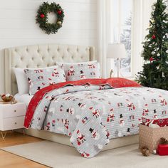 a christmas themed bed in a white bedroom with red and gray decorations on the walls