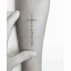 a person holding their arm with a cross tattoo on the left side of her leg