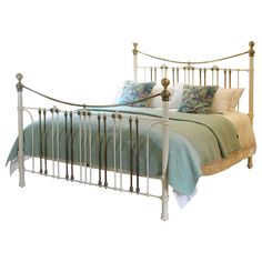 a white metal bed with blue and green pillows