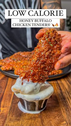 someone is dipping some kind of food into a cupcake on a plate with the words low calorie honey buffalo chicken tenders