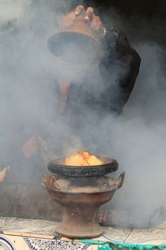 a man standing in front of a large pot filled with food