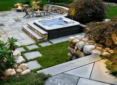 an outdoor hot tub surrounded by rocks and grass