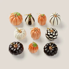 an assortment of miniature pumpkins on a white surface with black and orange ones in the middle