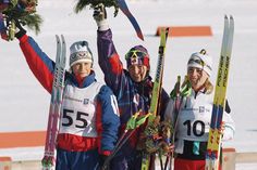 three people holding up their skis in the snow