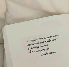 an open book with writing on it sitting on top of a white bed sheet covered in pillows