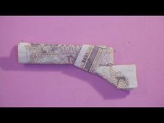 an origami money roll on a pink background