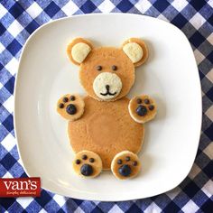 a teddy bear made out of pancakes on a plate with blue and white checkered tablecloth