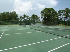 two tennis players on the same team playing in an outdoor court with trees and water behind them