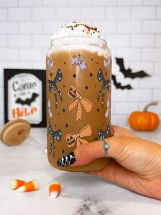 a hand holding up a glass with halloween decorations on it