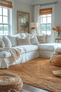 a large white couch sitting in a living room next to two windows with wicker baskets on the floor