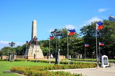 there are many flags flying in the air near a monument with a flag on it