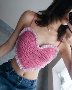 a woman taking a selfie in front of a mirror wearing a pink crocheted top