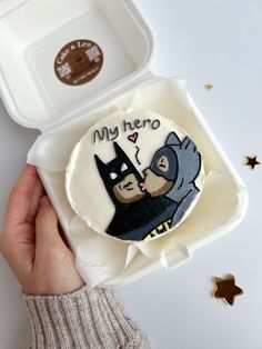 someone is holding up a cake decorated to look like batman and cat with the words my hero on it