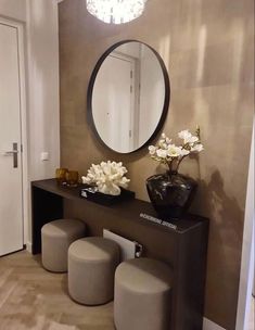 a mirror, stools and vase with flowers sit on a table in front of a doorway