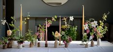 a table topped with lots of vases filled with different types of flowers and candles