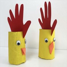 two paper cups with red and yellow roosters on them, one is made out of toilet paper