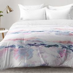 the comforter is made up with white sheets and pink and blue designs on it