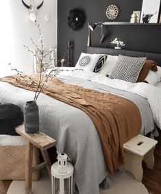 a bedroom with black walls and white bedding, brown blanket on the headboard