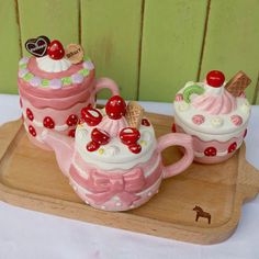 two pink teapots sitting on top of a wooden tray