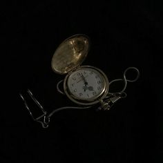 an antique pocket watch is sitting on the ground in the dark with its case open