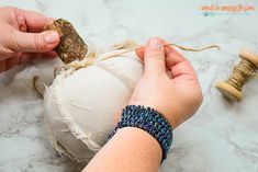 someone is making a beaded pumpkin decoration with yarn and twine on the table