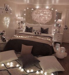 a bedroom decorated in white and black with lights on the headboard, bedding, rugs and pillows