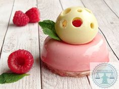 a dessert with raspberries on top of it and some green leafy garnish