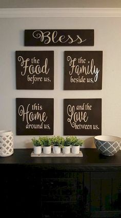 four signs are hanging on the wall above a black buffet table with white dishes and planters