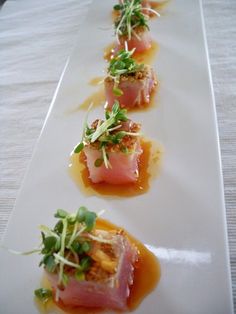 small appetizers are arranged on a white plate with sauce and garnishes