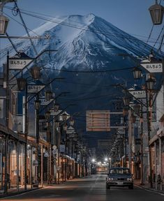 a car is driving down the street in front of a snow - capped mountain at night