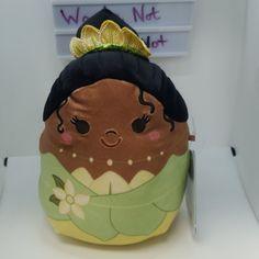 a stuffed toy with a green dress and gold crown sitting on top of a table