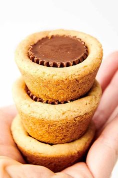 three peanut butter cupcakes stacked on top of each other in the palm of someone's hand