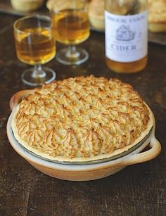 a pie sitting on top of a wooden table next to wine glasses