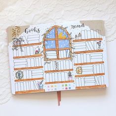 an open notebook with a drawing of a house on the front and windows in the back