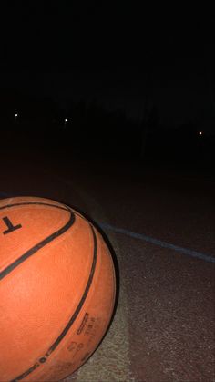 an orange basketball sitting on the ground at night