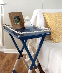 a blue tray with rope on it sitting on top of a wooden table next to a bed