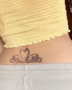 a woman with a tattoo on her stomach that has two swans in the shape of a heart