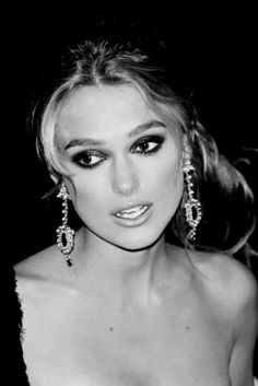 black and white photo of a woman with large earrings on her head, looking at the camera