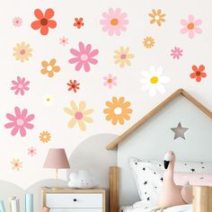 a child's bedroom decorated in pink, yellow and orange colors with flowers on the wall