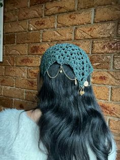 the back of a woman's head wearing a crocheted hat with chains