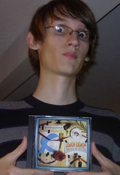 a young man holding up a book with an eyeball on it's face