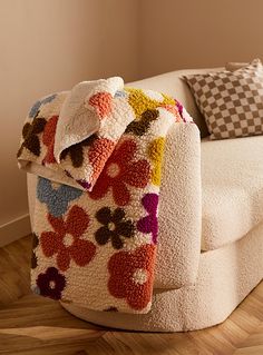 a couch covered in a colorful blanket on top of a hard wood floor