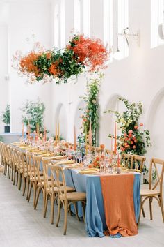 a long table is set with orange and blue linens for an elegant wedding reception