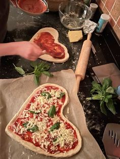 someone is making pizza in the kitchen with their heart shaped pizza cutters and rolling dough