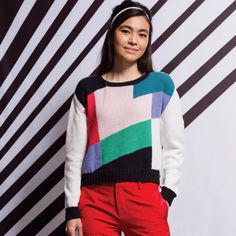 a woman standing in front of a black and white striped wall with the words, bridget sweater knitting pattern