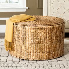 a large round wicker ottoman with yellow blanket on it's top and side