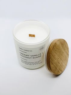 a candle with a wooden lid next to it on a white surface, which is also used as a container for creamery