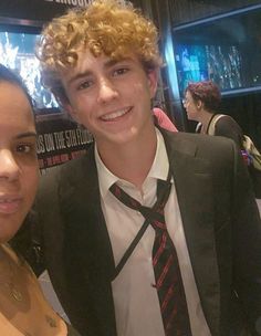 two young people are posing for the camera at an event, one is wearing a suit and tie